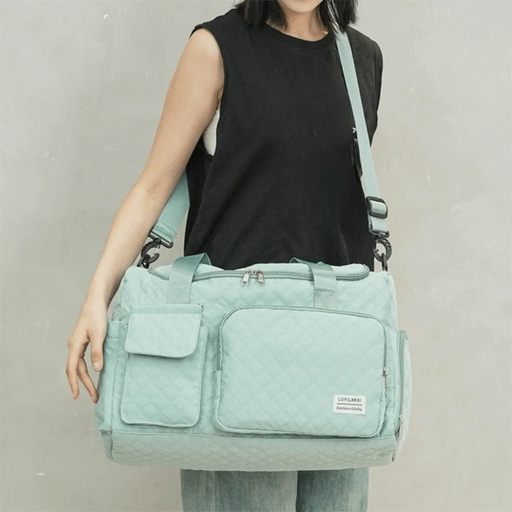 A light mint green quilted portable travel duffle bag worn by a person.