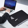 A person places an all-in-one laptop sleeve on a white desk next to an open laptop.
