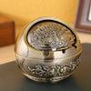 A vintage metal ashtray with a rose embossing design and a windproof lid, shown on a dark surface.