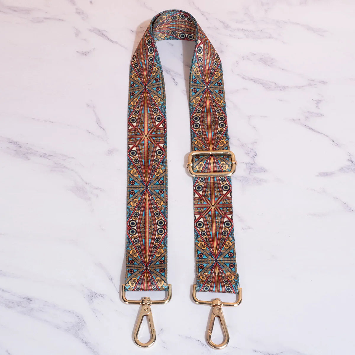 A close-up of a retro textile replacement bag strap featuring intricate geometric patterns in orange, blue, and brown on a wh