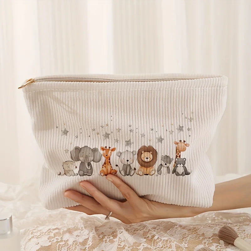A hand holds a white corduroy makeup storage pouch decorated with small elephant and lion illustrations.