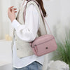 A woman wearing a beige vest and white shirt carrying a pink nylon crossbody bag.