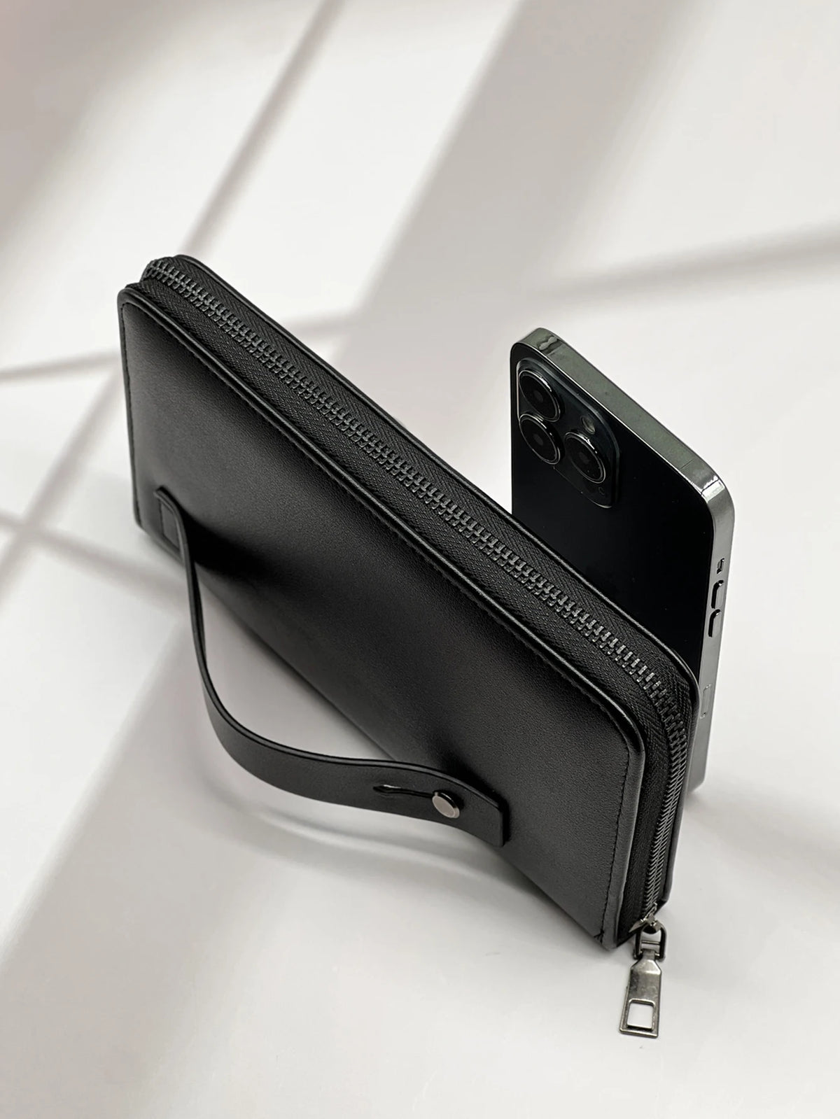 A black multi-card men's commuter wallet with a zipper and leather strap is shown against a bright background.