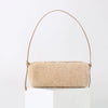 A beige vintage cow leather cylinder shoulder bag with a thin tan strap displayed on a white pedestal.
