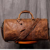 Braune Vintage-Leder-Tasche mit Ledergriff und Trageriem auf Holzoberfläche.