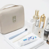 A beige waterproof makeup organizer and travel pouch with various cosmetic products displayed on a white surface.