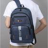 A navy blue lightweight commuter backpack worn by a man, featuring orange stripes and a SPORT logo.