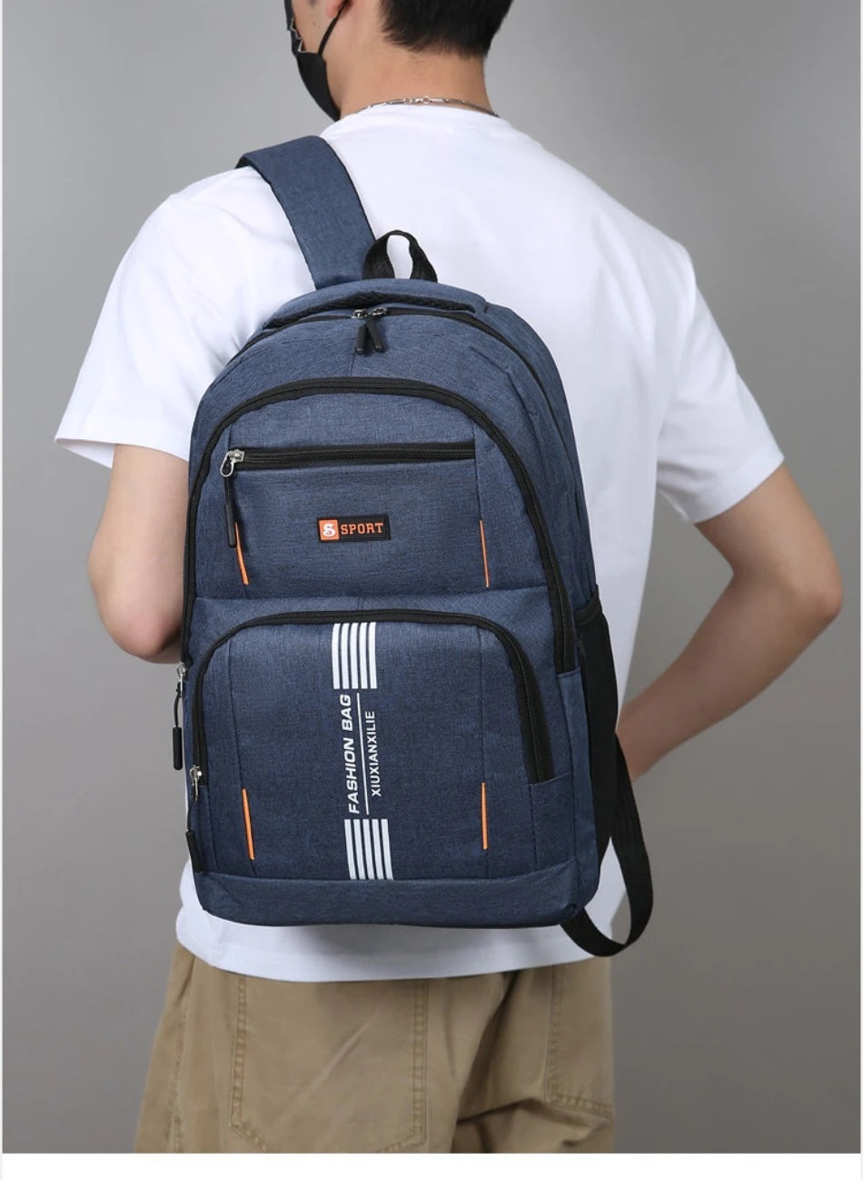 A navy blue lightweight commuter backpack worn by a man, featuring orange stripes and a SPORT logo.