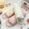 A collection of quilted storage bags in pink and white fabric are displayed on a white surface.