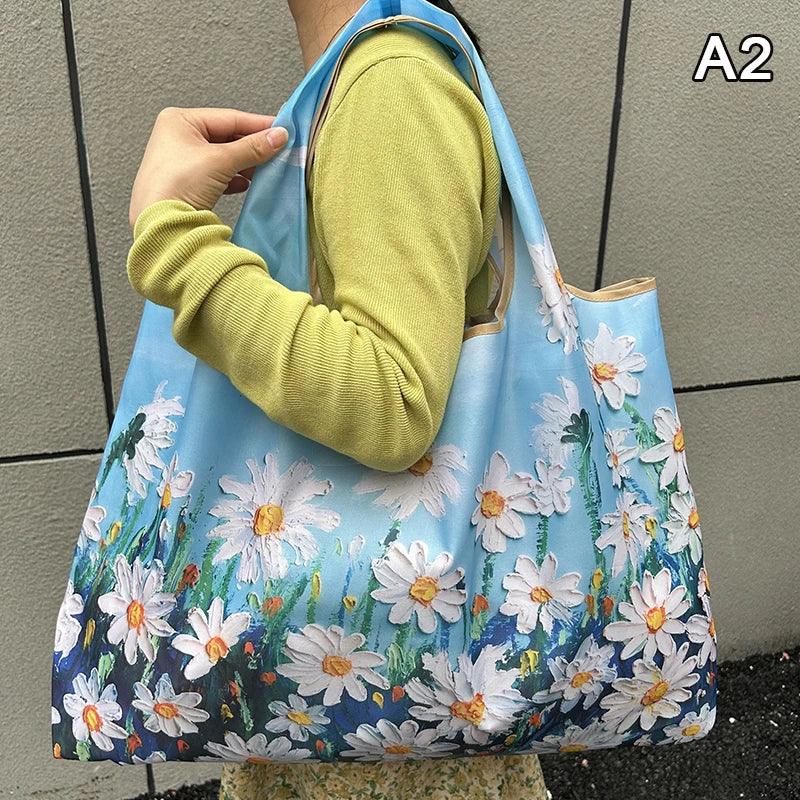 A light blue nylon shopping tote bag featuring a white and blue floral pattern, held by a person.