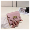 A pink leather card holder with a gold clasp is held next to a white linen cloth on a light surface.