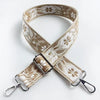 A beige and brown patterned jacquard strap for a crossbody bag, shown crossed.