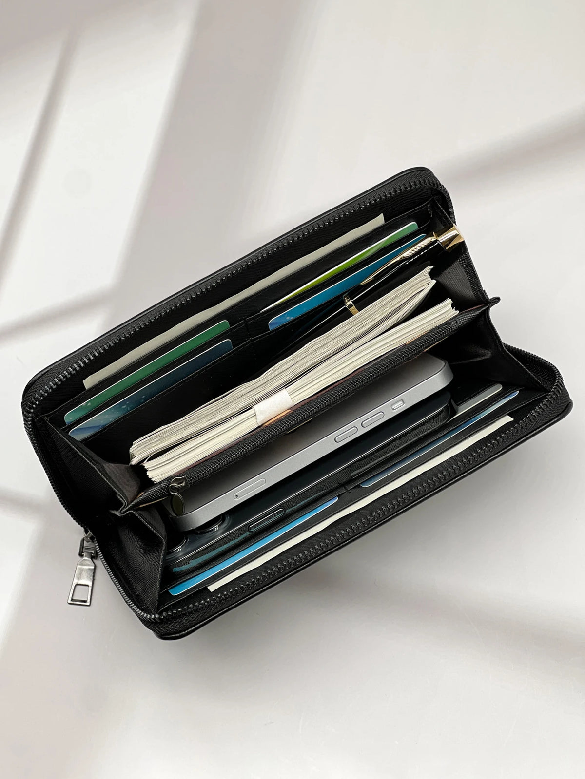 A black multi-card commuter wallet is shown open, displaying various cards and a smartphone.