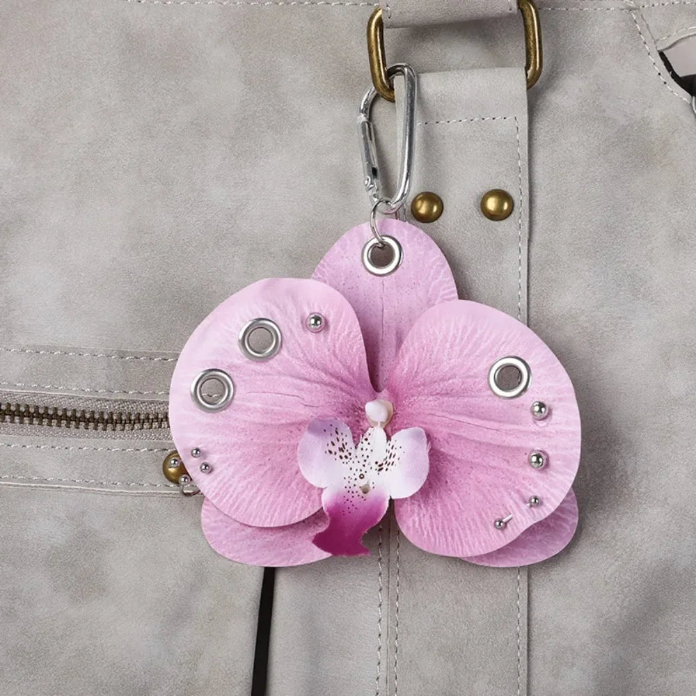 A realistic pink phalaenopsis orchid flower keychain attached to a gray fabric zipper pull.