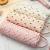 Three quilted storage bags in pink and white fabric stacked on a white surface.