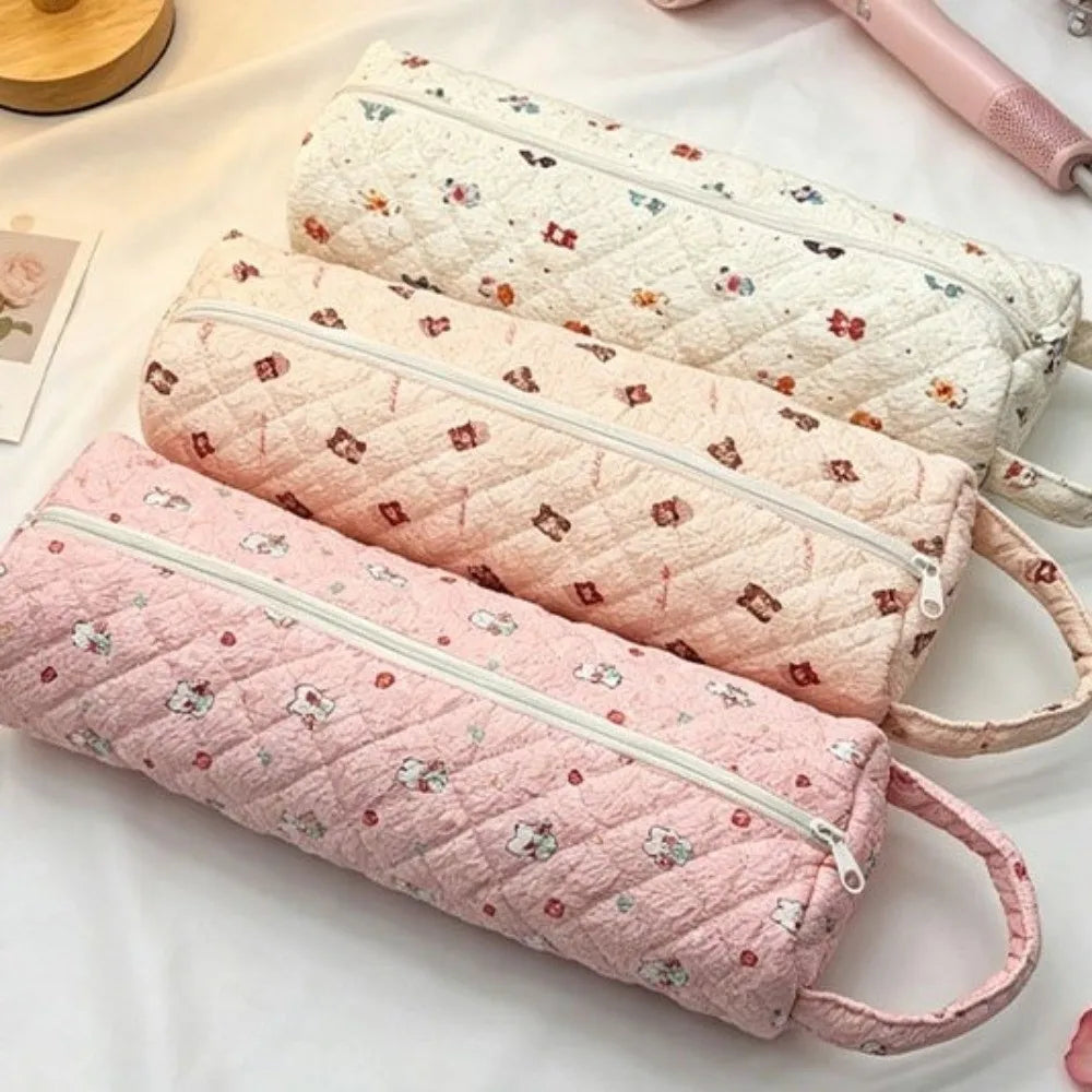 Three quilted storage bags in pink and white fabric stacked on a white surface.