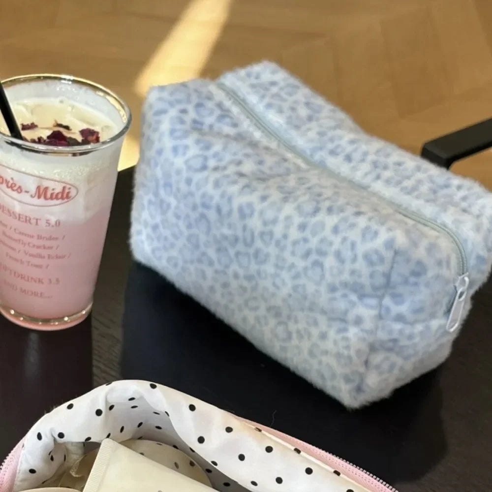 Bolsa de almacenamiento acolchada con cremallera floral azul claro junto a una bebida rosa.