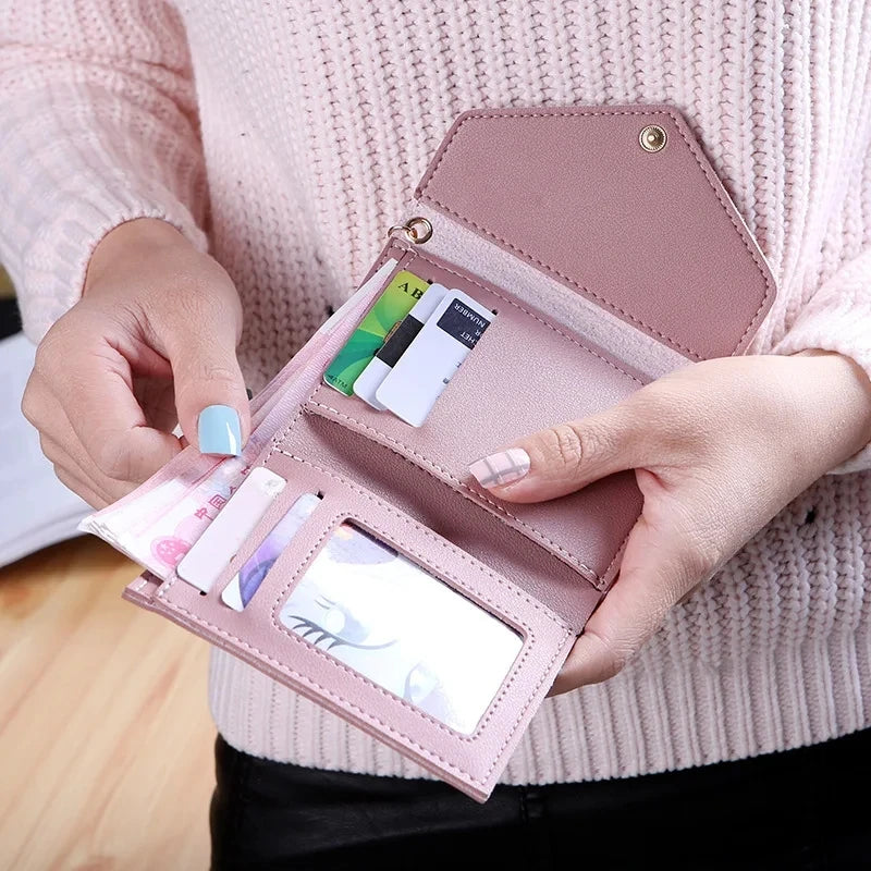 A hand holds a pink waterproof nylon crossbody bag displaying several credit cards and an ID card.