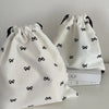 A white canvas makeup bag with black bowknot detailing is shown in a close-up view.