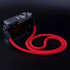 A black camera with a red adjustable strap is shown against a dark background.