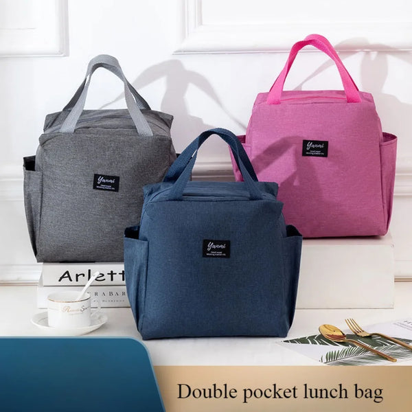 A set of three insulated canvas tote bags in gray, pink, and blue are displayed on a white surface.
