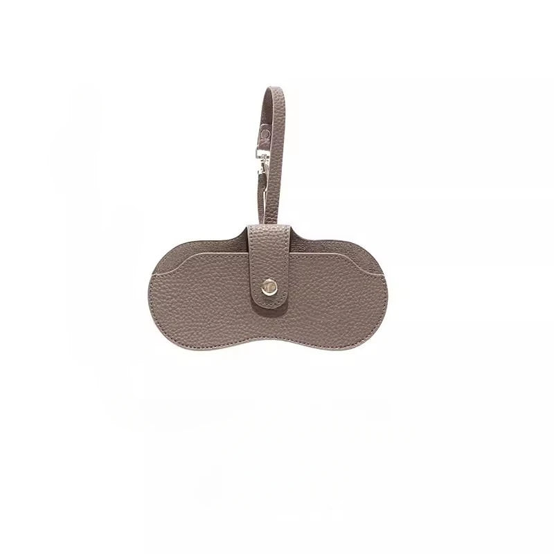 Estuche delgado de cuero gris claro para gafas de sol con cierre de correa.