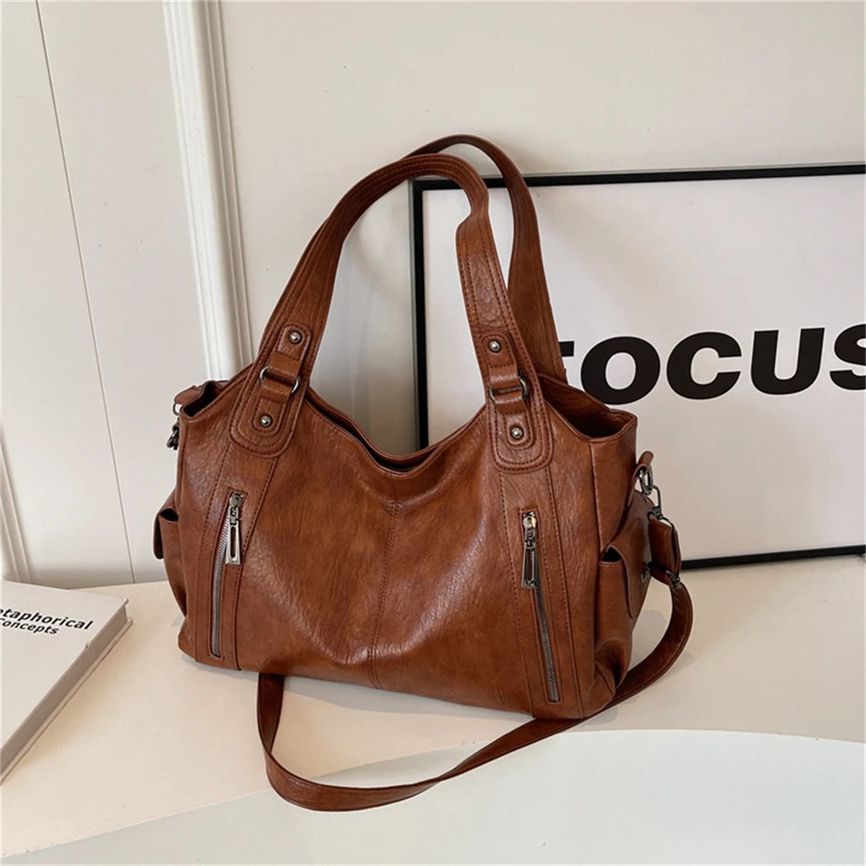 Un sac cabas en cuir marron à multiples poches, présenté sur une surface blanche.