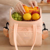 Una bolsa reutilizable aislada color melocotón claro con fruta fresca, sostenida por las manos de una persona.