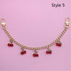 Gold chain necklace with red bead pendants displayed against a pink background.
