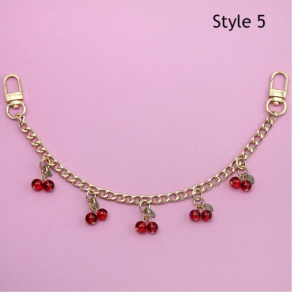 Gold chain necklace with red bead pendants displayed against a pink background.