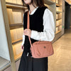 Una mujer con chaleco negro y camisa blanca sostiene un bolso cruz a juego de nylon impermeable rosa.