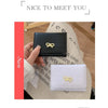 Une main tient un porte-cartes portefeuille PU noir plié et un portefeuille PU blanc plié.