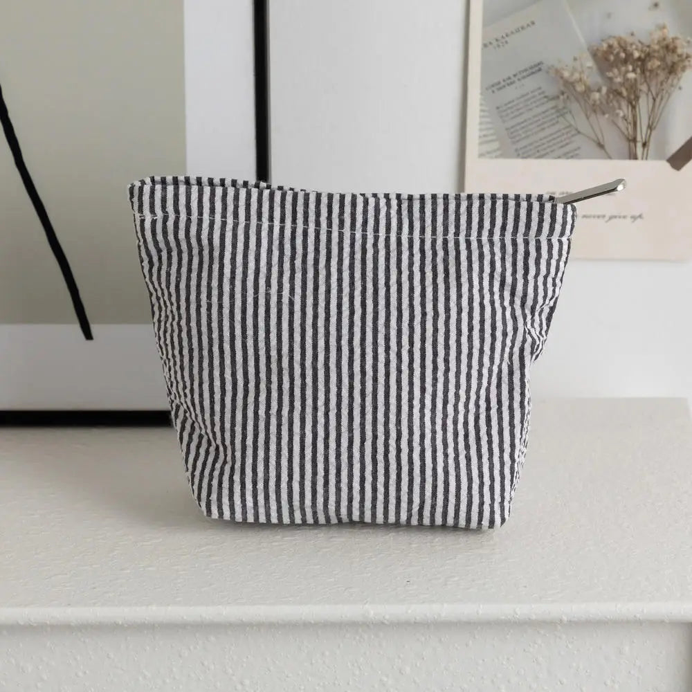 Pochette en crochet rayée tissée, noire et blanche verticales, posée sur une surface blanche.