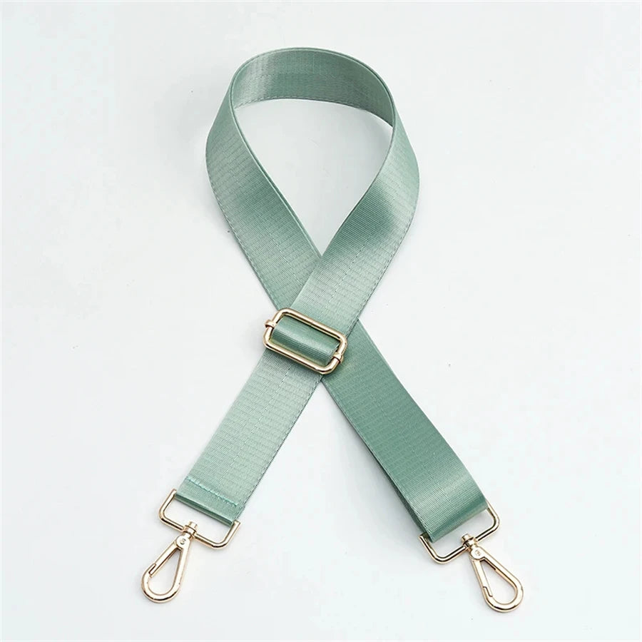 A light sage green adjustable nylon shoulder strap with a gold-toned buckle and metal hardware.