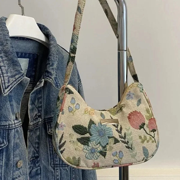 A vintage floral corduroy mini shoulder bag hanging on a hanger.