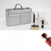A gray fabric handbag with a handle is shown next to various cosmetic and beauty products.