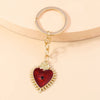 Gold heart keychain featuring a red gemstone pendant with sun eye details.