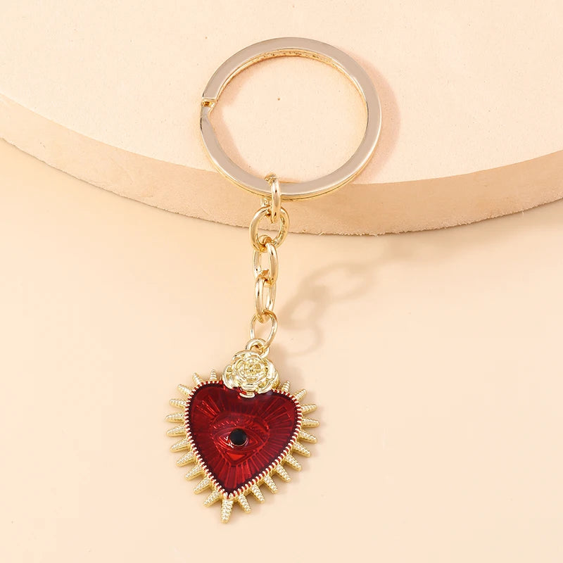 Gold heart keychain featuring a red gemstone pendant with sun eye details.