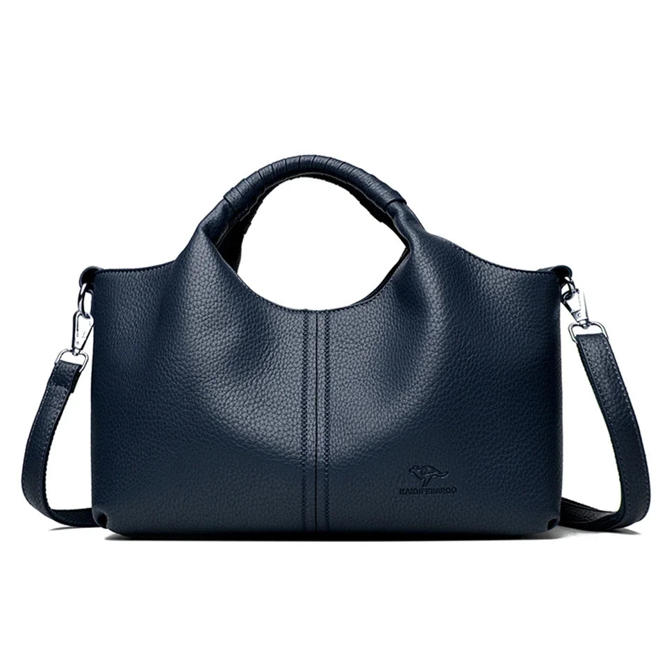 A dark navy blue luxury soft leather women's tote bag with a handle and shoulder strap.