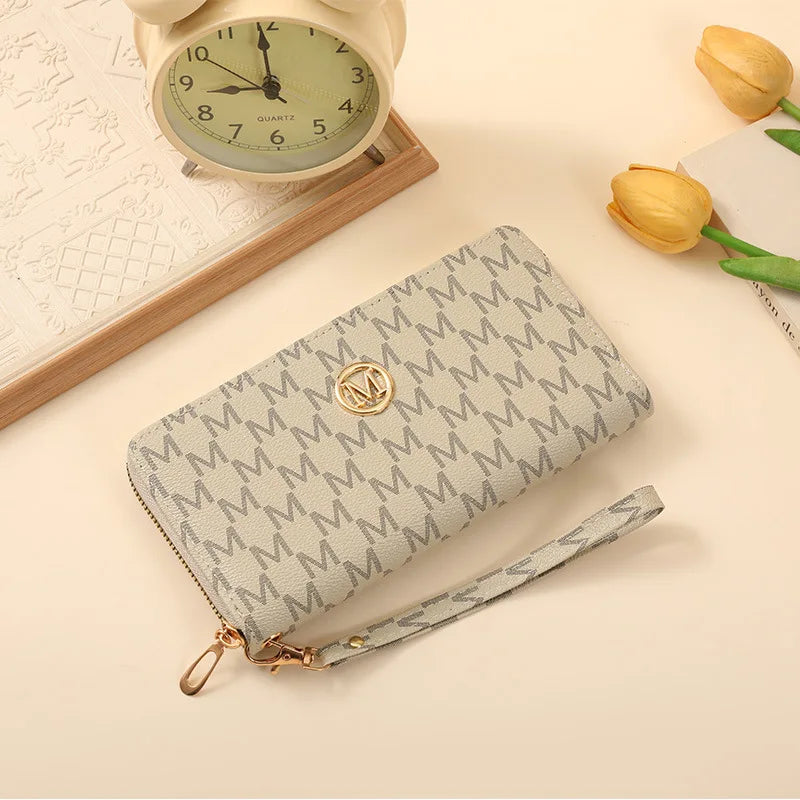 A beige patterned zipper wallet with a gold accent is shown next to a vintage-style clock and a yellow rose.