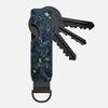 Porte-clés organisateur en métal minimaliste avec motif camouflage bleu foncé et or et une clé noire.