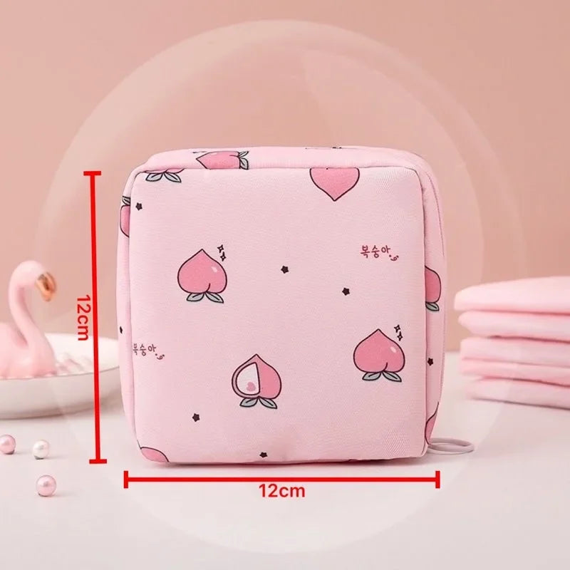 Pink compact sanitary pad storage pouch with a heart pattern and small stars shown on a white surface.