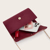 A deep burgundy velvet evening clutch with a gold chain strap and a clear window showing a pink card.