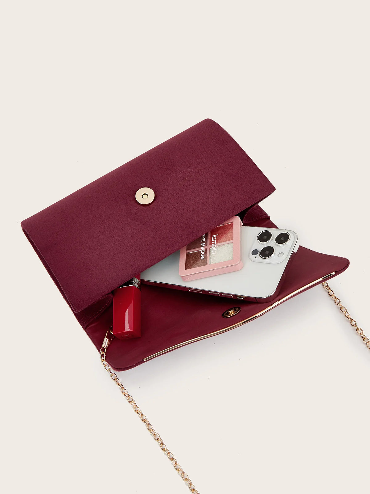 A deep burgundy velvet evening clutch with a gold chain strap and a clear window showing a pink card.