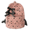 A pink corduroy backpack with a black bow print design and flap pockets.