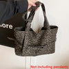 A hand holds a leopard print casual tote bag with dark brown and black patterns against a white background.