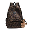 A brown leopard print backpack with a black strap and a small teddy bear charm.