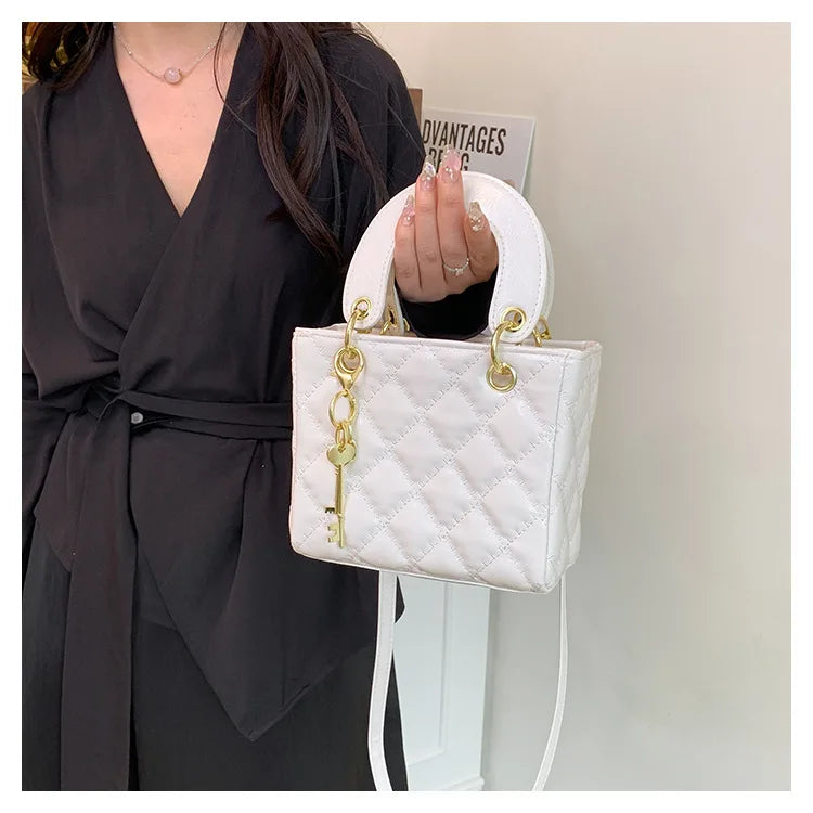 A woman holds a white diamond grid textured crossbody bag with gold hardware against a light background.
