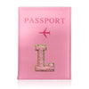 A pink leather passport holder with the word PASSPORT and a gold initial L embossed on it.