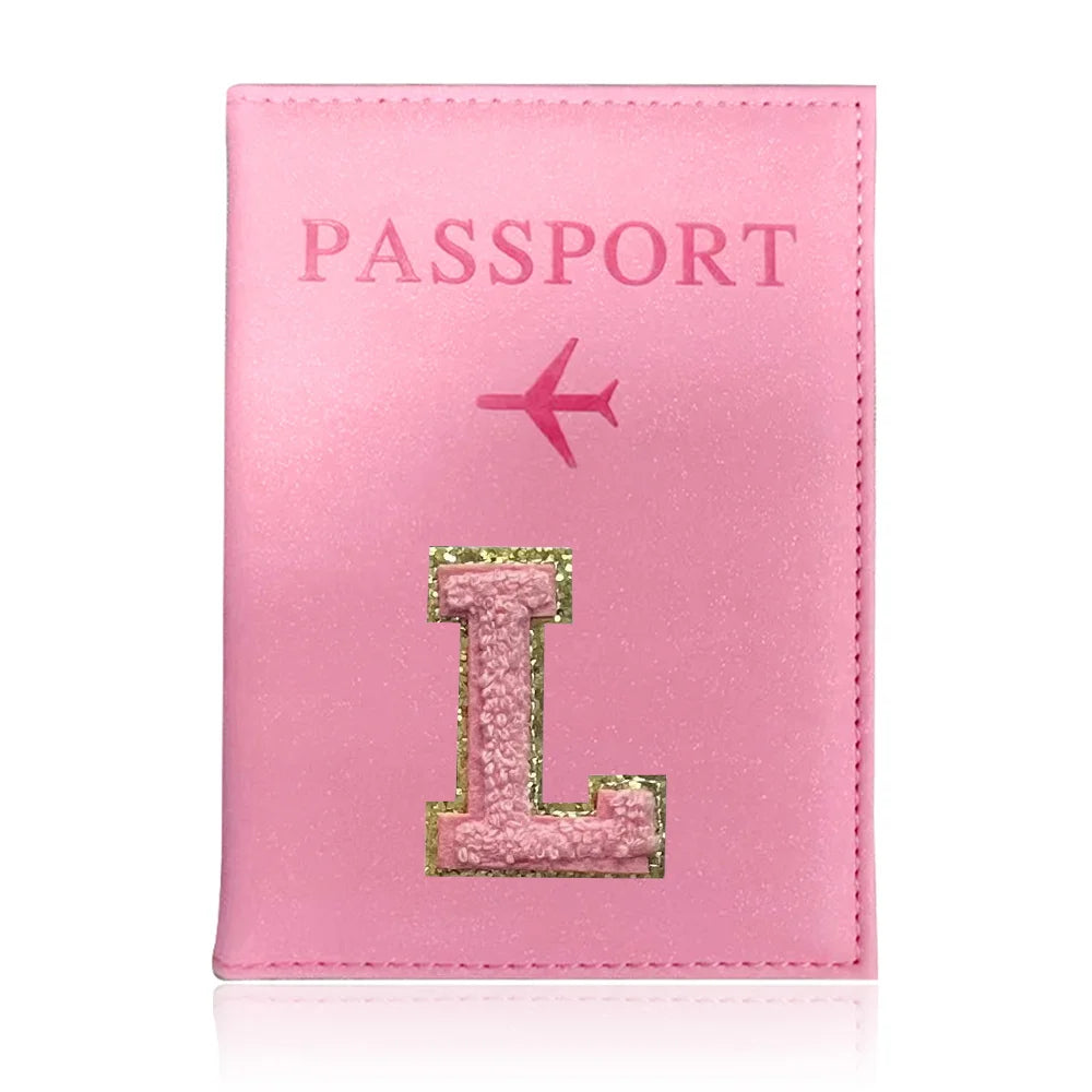 A pink leather passport holder with the word PASSPORT and a gold initial L embossed on it.